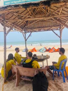 a group of people sitting at a table on the beach at Mui Ne Garden Hotel and Kite School in Mui Ne