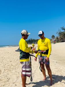 two men standing on a beach holding onto a string at Mui Ne Garden Hotel and Kite School in Mui Ne
