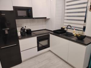 a kitchen with white cabinets and black appliances at Milan Luxury Apartaments II-Maurer Residence in Târgu-Mureş