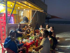 a group of people sitting around a table on the beach at Mui Ne Garden Hotel and Kite School in Mui Ne