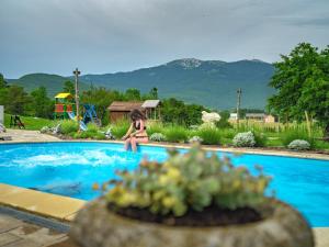 una mujer en bikini sentada al borde de una piscina en Holiday Park Plitvice Paradise, en Korenica