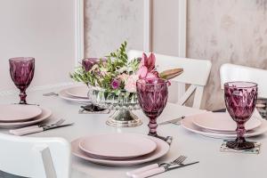 uma mesa com copos e pratos roxos e um vaso de flores em ARI Rose Apartment in complexul Ared Kaufland em Arad