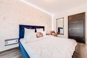 um quarto com uma grande cama branca e uma cabeceira azul em ARI Rose Apartment in complexul Ared Kaufland em Arad