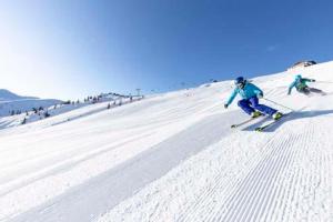 two people are skiing down a snow covered slope at Riedhof in Brandenberg