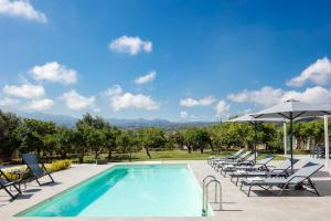 a swimming pool with lounge chairs and an umbrella at Angeliana Villa in Angeliana
