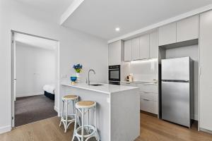 kuchnia z białymi szafkami oraz kuchnia z krzesłami w obiekcie Elegant 1-Bed by Shops with Rooftop Swimming Pool w Melbourne