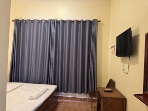 1 dormitorio con cama y cortina azul en Samrongsen Hotel, en Kampong Chhnang