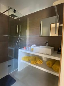 La salle de bains est pourvue d'un lavabo, d'une douche et de serviettes jaunes. dans l'établissement Casa Felicia, à Bonifacio