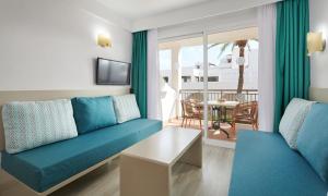 sala de estar con sofá azul y mesa en Apartamentos Cala d'Or Playa, en Cala d´Or