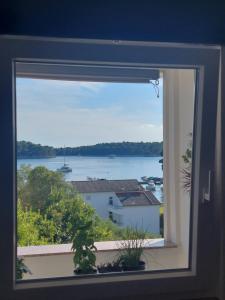 a window with a view of a body of water at Apartmans and rooms Petra in Rab
