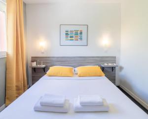 - une chambre avec un grand lit blanc et des oreillers jaunes dans l'établissement Hôtel Lapeyronie, à Montpellier