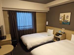 Hotel Route-Inn Oshu في Oshu: غرفة فندقية بسريرين ونافذة