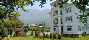 a white house with mountains in the background at Whostels Srinagar in Srinagar