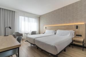 a hotel room with a large bed and a desk at Hotel Blanca de Navarra in Pamplona