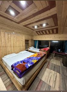 two beds in a room with wooden walls at Parasharalya luxury home stay in Prashar lake