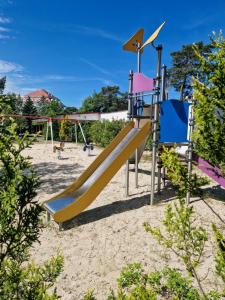 a playground with a slide in the sand at Dom Wypoczynkowy Słoneczna in Ustka