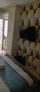 sypialnia z łóżkiem i ścianą z telewizorem w obiekcie Attic place South B. w mieście Nairobi