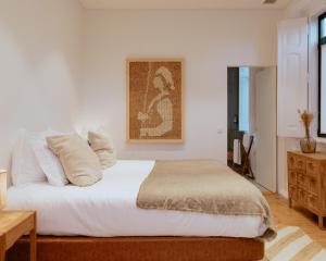 a bedroom with a bed with white sheets and pillows at A Casa Brava in Santarém +61 photos