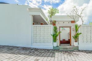 uma casa branca com vasos de plantas em frente em Belvilla 93868 Hii Inn em Uluwatu