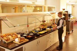 a woman standing in a kitchen preparing food at H+ Hotel Stade Herzog Widukind in Stade