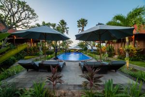 a pool with chairs and umbrellas in front of a resort at D'Puncak Villas Lembongan in Nusa Lembongan