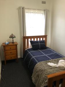 a bedroom with a bed and a window and a nightstand at Strangways Villa in Mount Gambier
