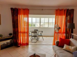 a living room with orange curtains and a table at Casa Vaso in Moncarapacho