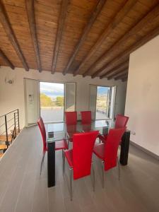 Un comedor con sillas rojas y una mesa de cristal. en Antica Dimora, en Termini Imerese