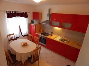 una cocina con armarios rojos y una mesa pequeña con mesa. en Apartmani Mastrinka, en Vinišće