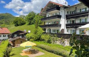 a large white building with a patio and a yellow umbrella at Hotel Restaurant Neu Meran in Bad Reichenhall