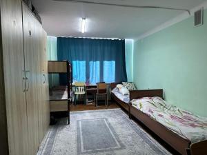a bedroom with two beds and a table and chairs at Student Castle Almaty hostel in Almaty