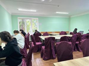 a group of people sitting in a room with purple chairs at Student Castle Almaty hostel in Almaty
