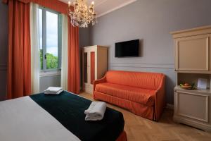a bedroom with a bed and a chair and a chandelier at Hotel Villa Carlotta in Florence