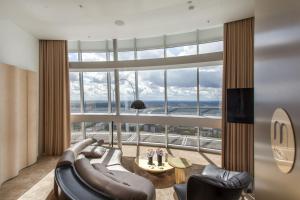 a living room with a couch and chairs and a large window at Vilnius TV Tower Apartments DEBESYS in Vilnius
