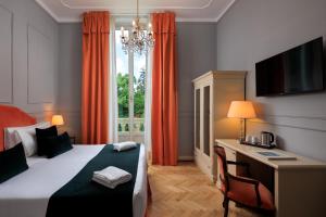 a bedroom with a bed and a desk and a window at Hotel Villa Carlotta in Florence