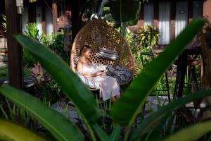 a woman sitting in a swing in a garden at D'Puncak Villas Lembongan in Nusa Lembongan