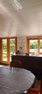 a kitchen with a table and a sink and two windows at Le Chalet du Viaur in Tanus