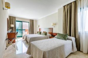 トレ・デル・マールにあるHotel Torremar - Maresのベッド2台とデスクが備わるホテルルームです。