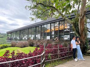 two people standing in front of a building with flowers at The Retreat Mountain n Sunrise view Hilltop Hotel Apartment in Cameron Highlands in Brinchang