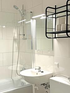 a white bathroom with a sink and a shower at Hammerhotel Apartments Halle Saale in Halle an der Saale