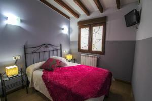 a bedroom with a bed with a pink blanket at Alojamientos Fermín in Cangas de Onís