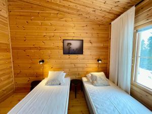 due letti in una stanza con pareti in legno di Matilda Villas, quality villas by the sea in the beautiful village of Mathildedal a Matildedal