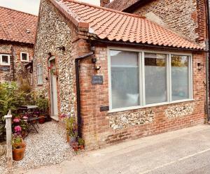 a brick house with a window and a table at The Old Candle Shop in Little Walsingham