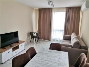 a living room with a couch and a tv and a table at Zigrabay lovely appartments in Primorsko