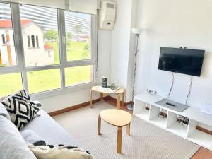a living room with a couch and a tv and a table at Apto HUCA-Prados Con Parking in Oviedo
