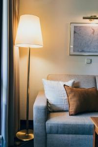a lamp sitting next to a couch with a pillow at Hotel Reindl Suiten & Appartments in Bad Füssing
