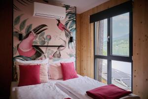een slaapkamer met een bed met roze kussens en een muurschildering met vogels bij Kantor Village am Millstätter See - Boutique-Chalets und Lodges in Millstatt
