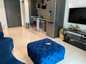 un salon avec un pouf bleu et une cuisine dans l'établissement Splendid Apartments - Embassy Gardens, à Accra