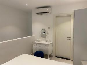 a white bathroom with a sink and a mirror at Splendid Apartments - Embassy Gardens in Accra
