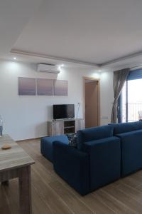 a living room with a blue couch and a tv at PARASCHOS APARTMENTS Kardamaina in Kos